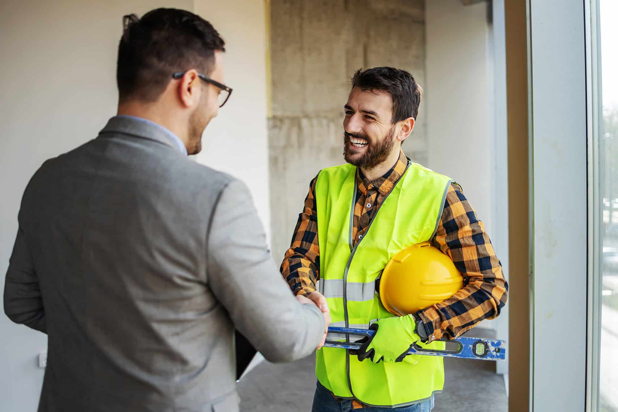 Smiling construction worker shaking hands with supervisor